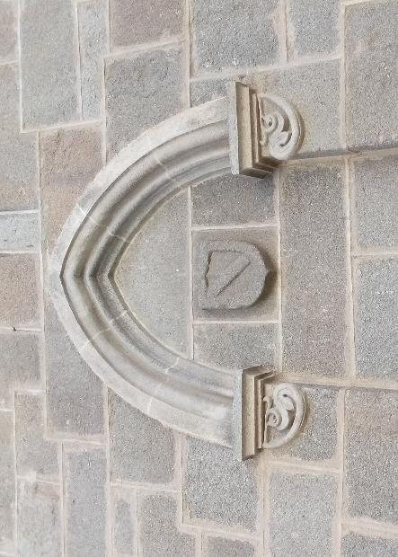 Pequeño escudo con banda enmarcado por un arco neogótico