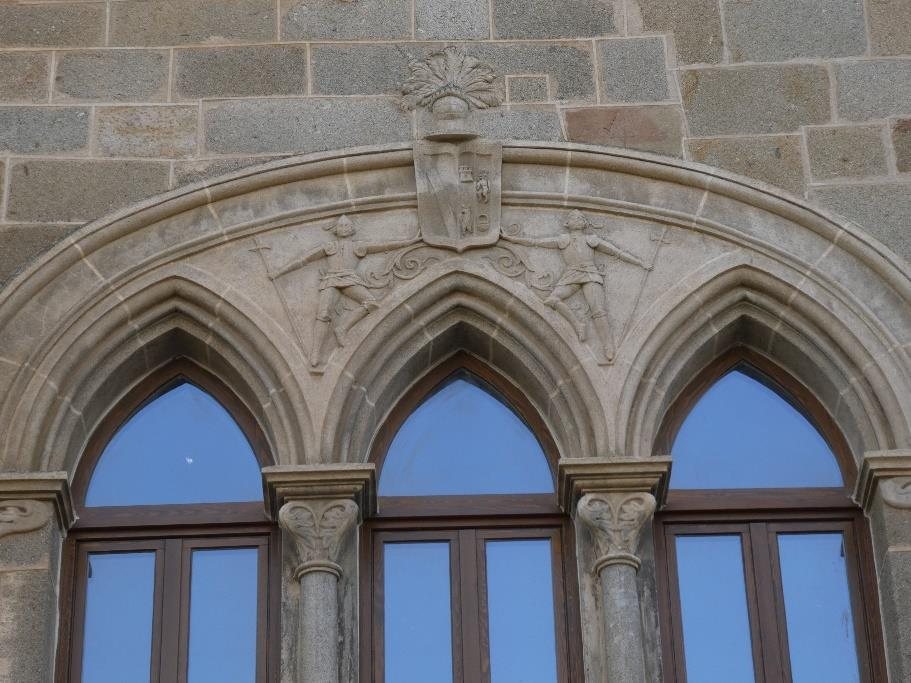 Ventana trífora neogótica coronada por un escudo
